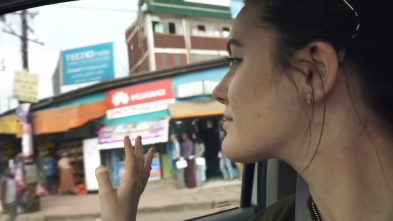 A Woman Waving from The Car Window While Passing Through a Busy Street in Ethiopia